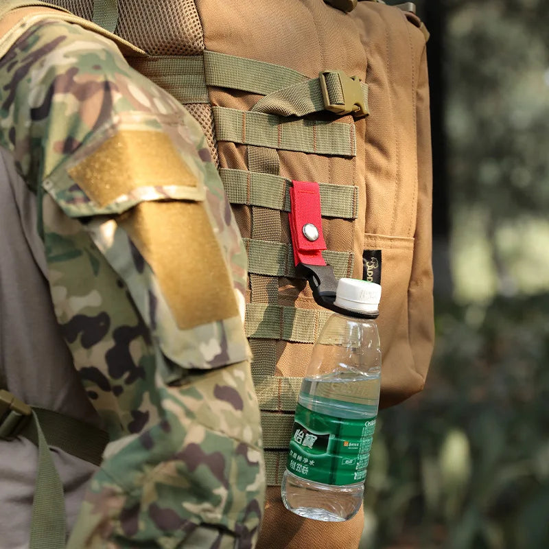 Person wearing a camouflage jacket and tactical vest with a water bottle attached, blurred background