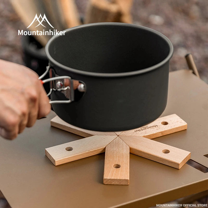 Black camping pot held by a hand on a camping table with 'Mountainhiker' branding.