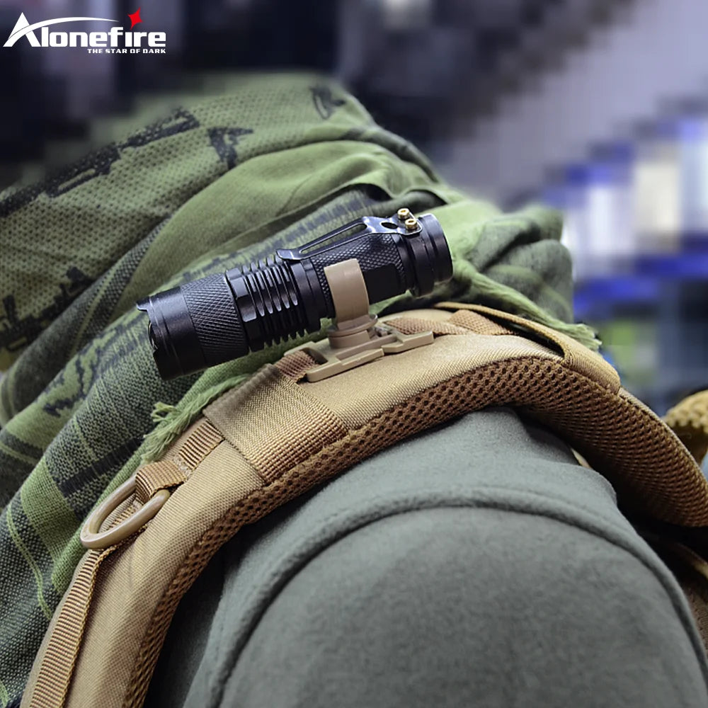 Black flashlight on a green and brown tactical backpack with 'Alonefire' branding.