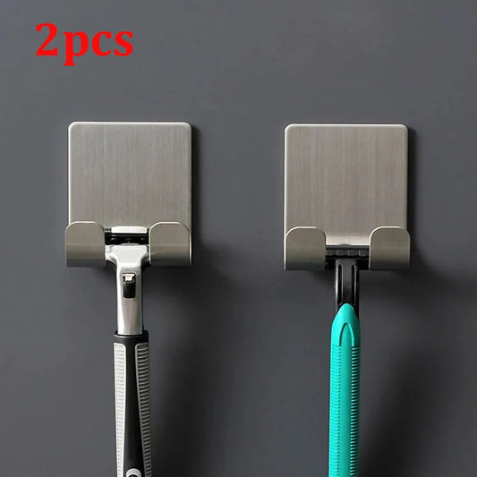 Two metal wall hooks holding razors on a dark gray background
