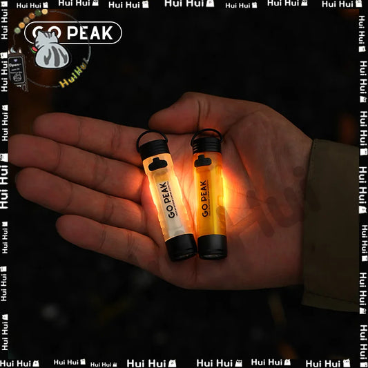 Two glowing 'GO PEAK' light sticks held in a hand with a dark background.