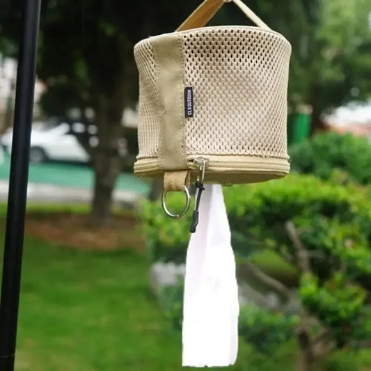 Beige pouch with mesh design and white tassel hanging outdoors