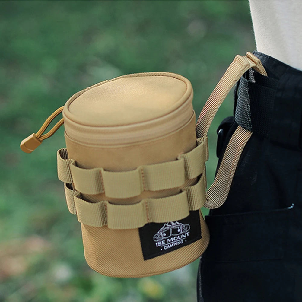 Tan tactical water bottle holder with a strap, featuring a brand logo, against a blurred green background.