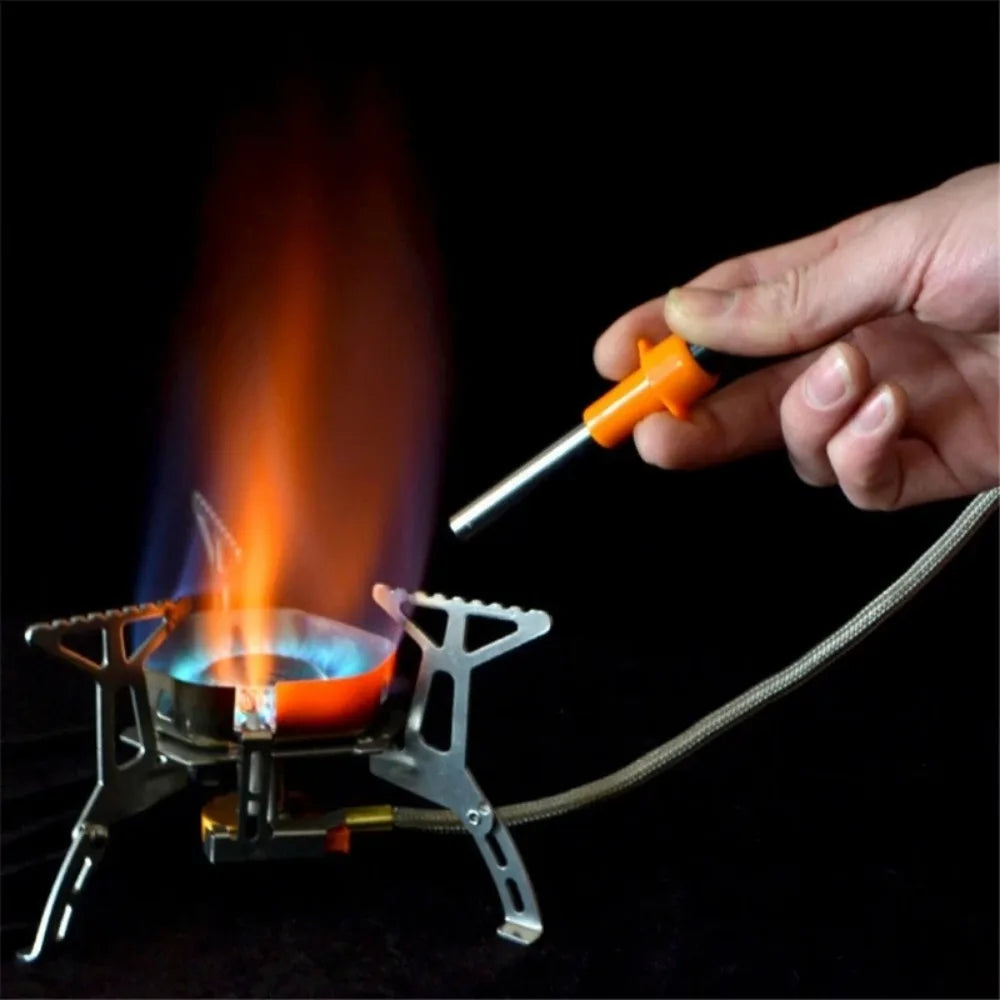 Hand using a lighter to ignite a small camping stove with flames on a black background