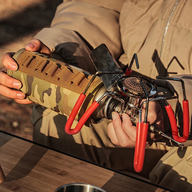 Person holding a portable stove with accessories on a wooden surface