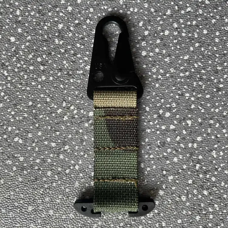 Green webbing strap with black clip on a gray textured background